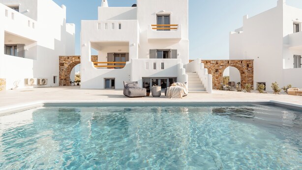 Un edificio moderno bianco con piscina, archi in pietra e area relax all'aperto.