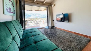 A green sofa, a TV, and a balcony with a view. - View Lake Attic in Ioannina (Ioannina)