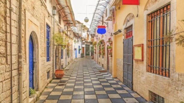 A narrow alleyway with checkered paving, stone buildings, and a red sign. - View Lake Attic in Ioannina (Ioannina)