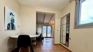 A room with a dining table, chairs, a large window, and a view of the outdoors. - View Lake Attic in Ioannina (Ioannina)