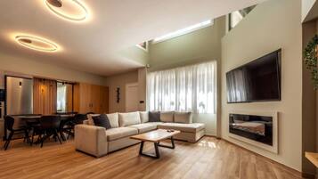 Relax in this stylish living room with a large L-shaped sofa, flat-screen TV, and fireplace.