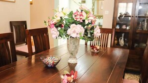 A wooden dining table with a vase of pink flowers, a bowl of candy, and a small dish of dried fruit. - Garden House Kastellani -corfu Greece Free Wi-fi (Corfu)