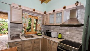 A compact kitchen with wooden cabinets, a stainless steel stove, a microwave, and a sink. - Garden House Kastellani -corfu Greece Free Wi-fi (Corfu)
