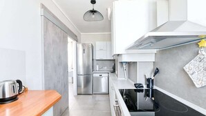 A modern kitchen with stainless steel appliances, a wooden countertop, and a black induction cooktop. - The Bridge - Peschiera Holiday (Peschiera del Garda)