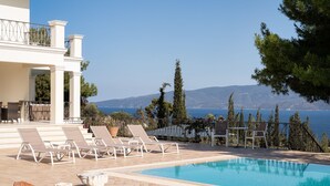 Un espace piscine avec des chaises longues et vue sur la mer.