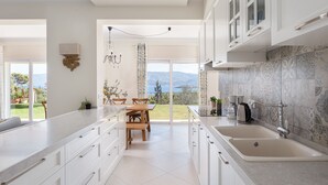 Une cuisine moderne avec des meubles blancs, un grand îlot central et une vue sur l’extérieur.