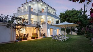 Une maison à deux étages dotée d’un balcon, d’un espace extérieur aménagé pour s’asseoir et d’une pelouse bien entretenue.
