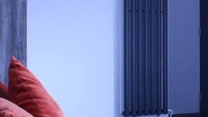 Una habitación con un radiador, una puerta y una almohada roja.