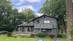 Een tweelaags huis met een terras en een omheinde tuin.