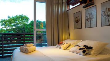 Una camera da letto con un letto grande, molti cuscini, vista sul verde e opere d'arte alle pareti.