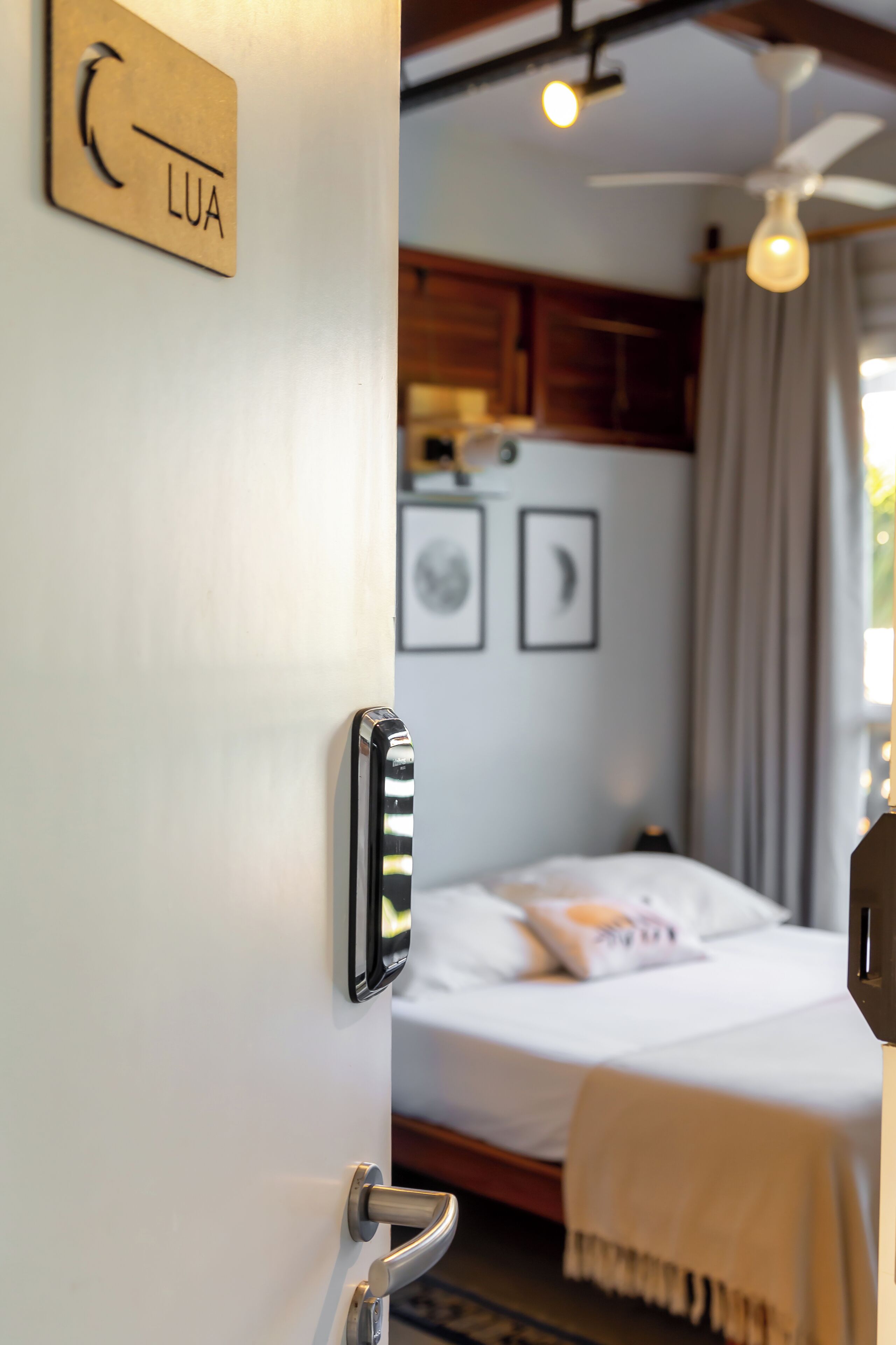 A hotel room with a bed, a ceiling fan, and a door with a handle.