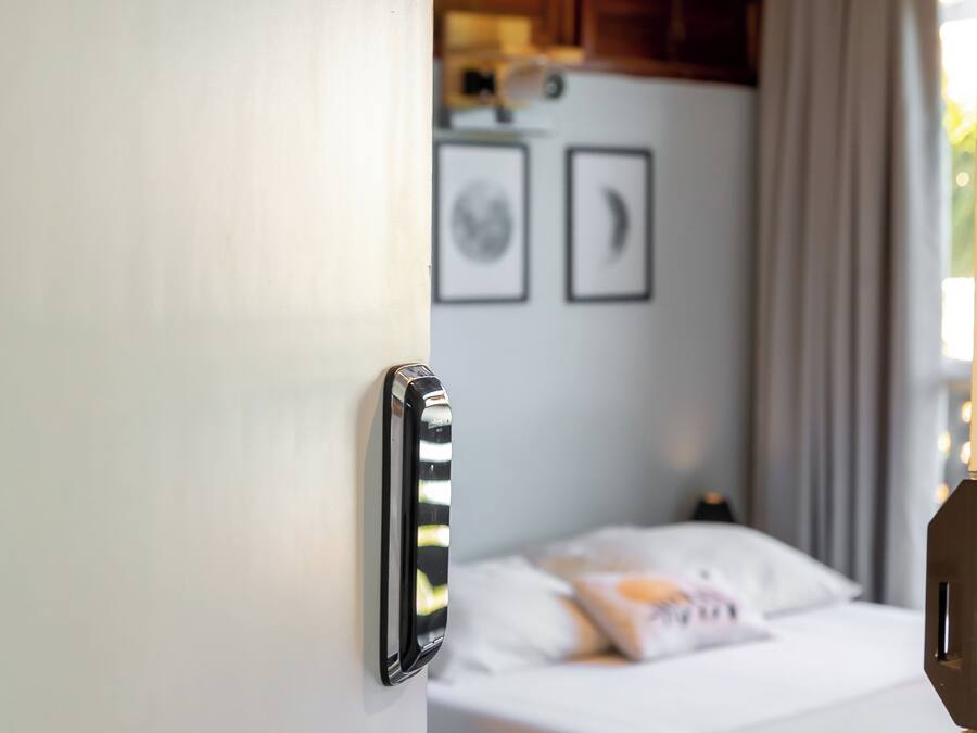 A hotel room with a bed, a ceiling fan, and a door with a handle.