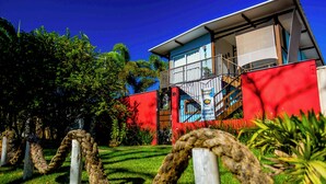 A modern building with a red facade, a balcony, and a staircase leading to an upper level. - Pousada Contêiner 10 (Serra)