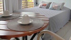 A bedroom with a bed, a table with a cup and saucer, and a ceiling fan. - Pousada Contêiner 10 (Serra)