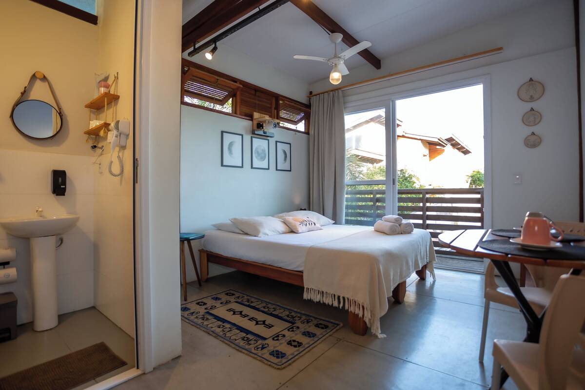Un dormitorio con cama, mesita de noche, una silla, una ventana y vistas al exterior.