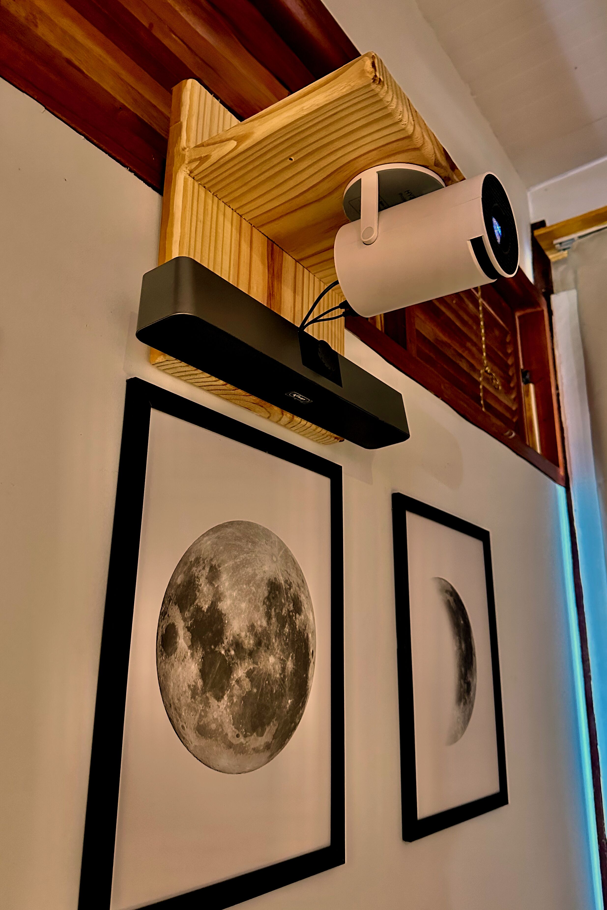 A ceiling-mounted security camera, framed artwork of the moon, and a wooden shelf.
