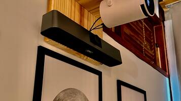 A ceiling-mounted security camera, framed artwork of the moon, and a wooden shelf.