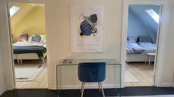 A room with a glass table, a blue chair, and a framed artwork on the wall.
