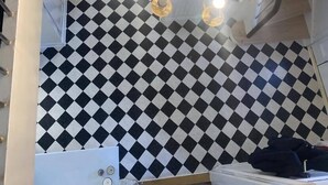 Una cocina moderna con un salpicadero a cuadros blanco y negro, una campana extractora de acero inoxidable y una lámpara de araña con varias bombillas.