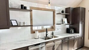 Une cuisine moderne avec des carreaux de céramique blancs disposés en motif métro, un four encastré, un évier en acier inoxydable et des armoires en bois.