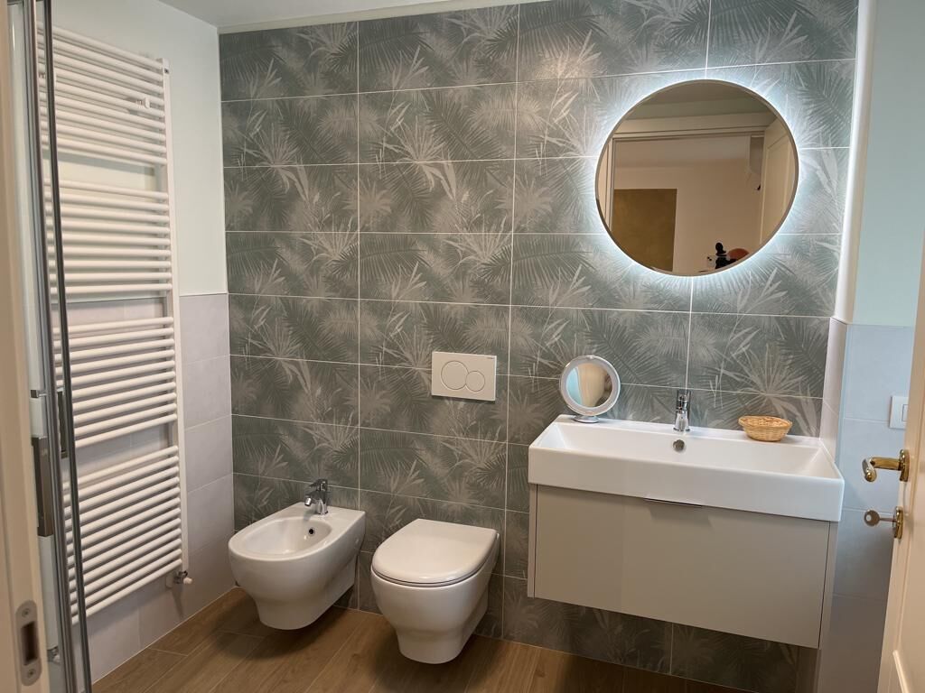 Une salle de bain équipée d’un bidet, de toilettes, d’un meuble-lavabo avec miroir et d’un porte-serviettes.