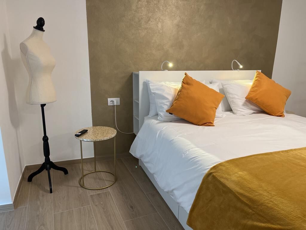 Ein Hotelzimmer mit einem Bett, einer Stehlampe, einem kleinen runden Tisch und einer Schönheitsmannequin.