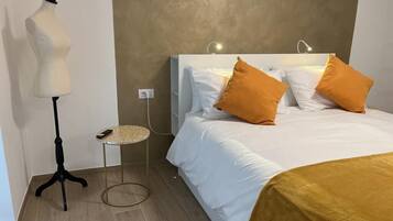 Ein Hotelzimmer mit einem Bett, einer Stehlampe, einem kleinen runden Tisch und einer Schönheitsmannequin.