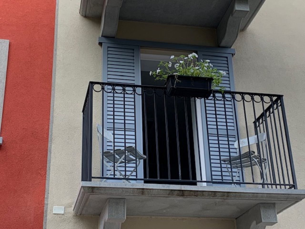 A balcony with a black metal railing, a small table, and a potted plant.