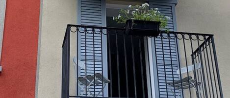 A balcony with a black metal railing, a small table, and a potted plant.