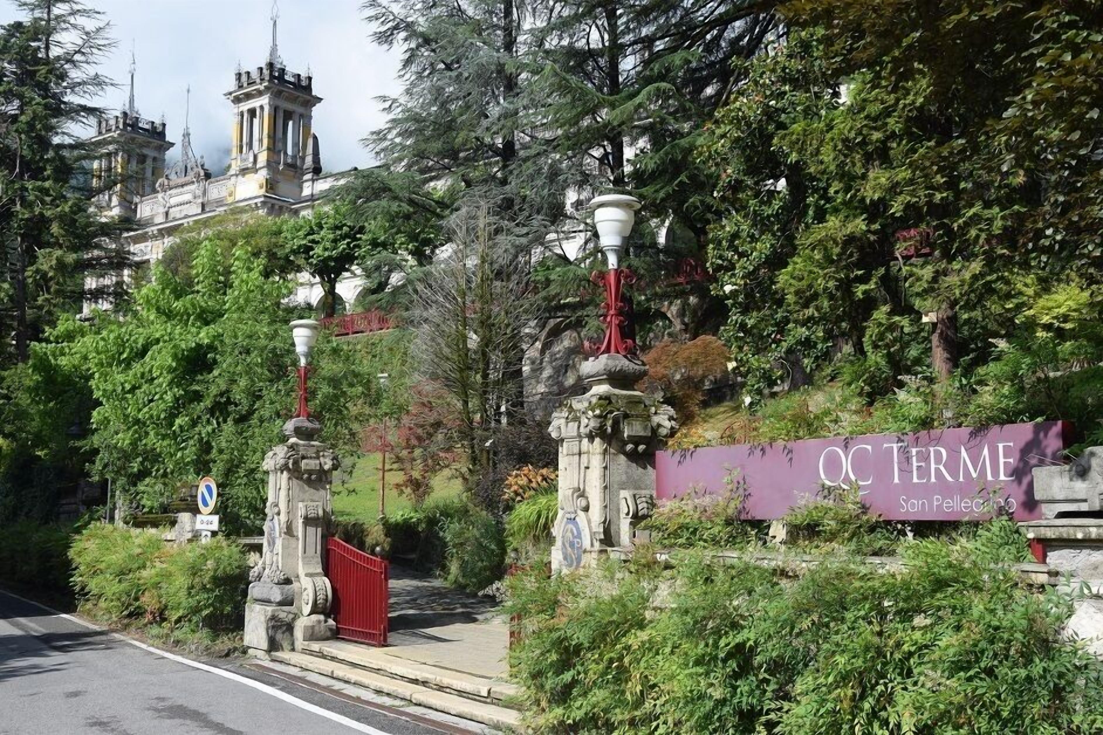 A historic building with ornate architecture, a red gate, and a sign reading "QC TERME San Pellegrino."