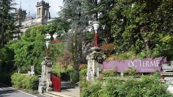A historic building with ornate architecture, a red gate, and a sign reading "QC TERME San Pellegrino."