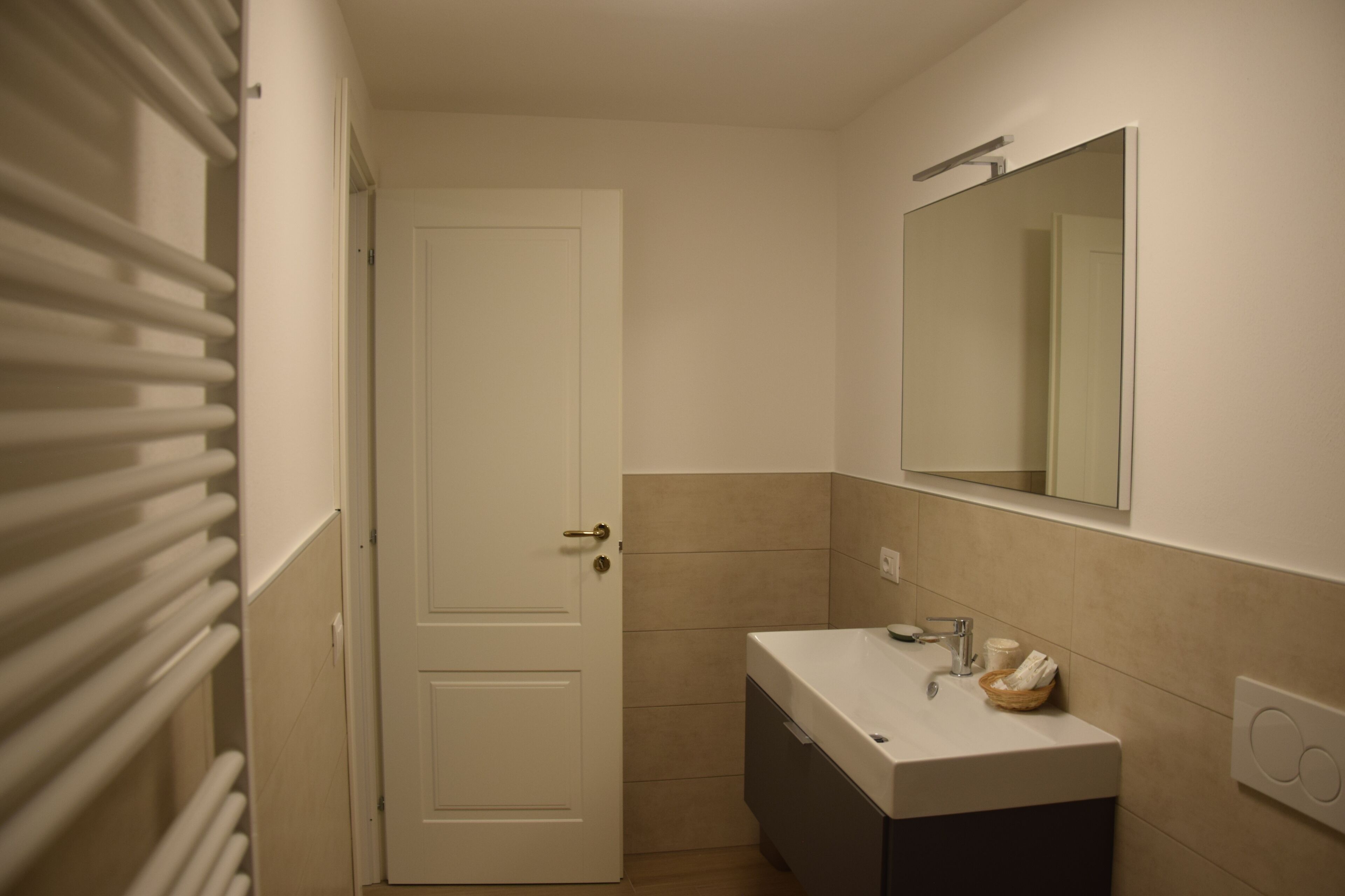A bathroom with a white door, a sink with a mirror above it, and a towel on the counter.