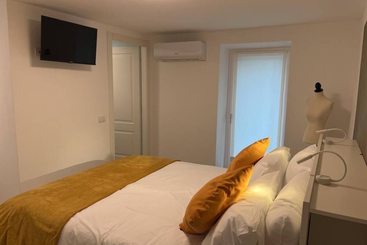 Ein Hotelzimmer mit Bett, Wandfernseher, Klimaanlage, Fenster mit Blick und einer Büstenpuppe.