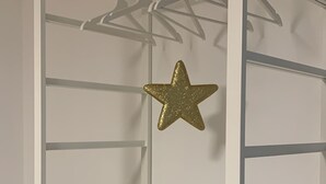 Een witte inloopkast met meerdere planken en een sterofficial decoratie.
