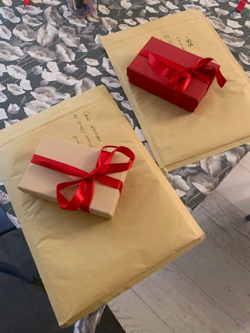 Dos cajas de regalo con lazos rojos sobre un mantel con estampado floral.