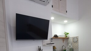 Cozinha compacta com televisão de tela plana, pequena mesa de jantar e forno embutido.