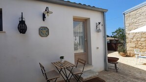 Um edifício branco com porta de madeira, janela com cacto, lanterna na parede e um prato decorativo.