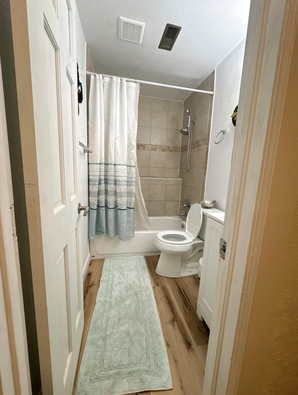 Ein Badezimmer mit Dusche, Toilette und einem kleinen Teppich.