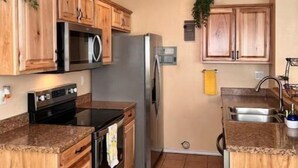 A kitchen with wooden cabinets, a stainless steel refrigerator, a microwave, and a stove.