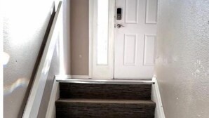 A staircase with dark wooden steps and white trim, leading to a white door with a small window above it.