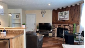 A living room with a fireplace, a television, a sofa, and a dining area.