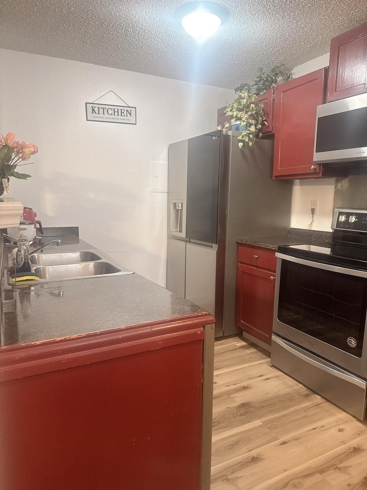 A kitchen with a stainless steel refrigerator, a built-in oven, and red cabinetry.