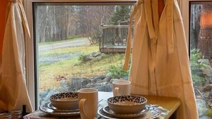 Ein Tisch mit Blick auf eine bewaldete Landschaft durch ein Fenster mit Vorhängen.