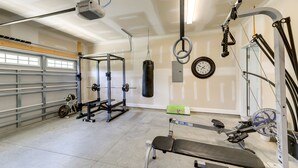 A home gym with a bench press, weight rack, punching bag, and various exercise equipment.