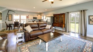 A spacious living room with a brown leather sofa, a coffee table, and a dining area with a table and chairs.