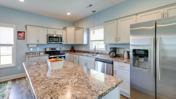 A modern kitchen with granite countertops, stainless steel appliances, and white cabinetry.