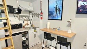 A compact kitchen with a microwave, sink, and wooden bar counter with two chairs. - Charming Studio Loft In Hollywood Beach, Free Parking (Hollywood)