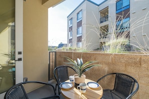 A balcony with a table, chairs, and a potted plant. - Beach Condo 234CB (Carlsbad)