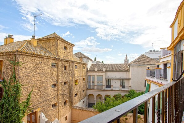 A courtyard with stone buildings, a balcony, and a clear sky.