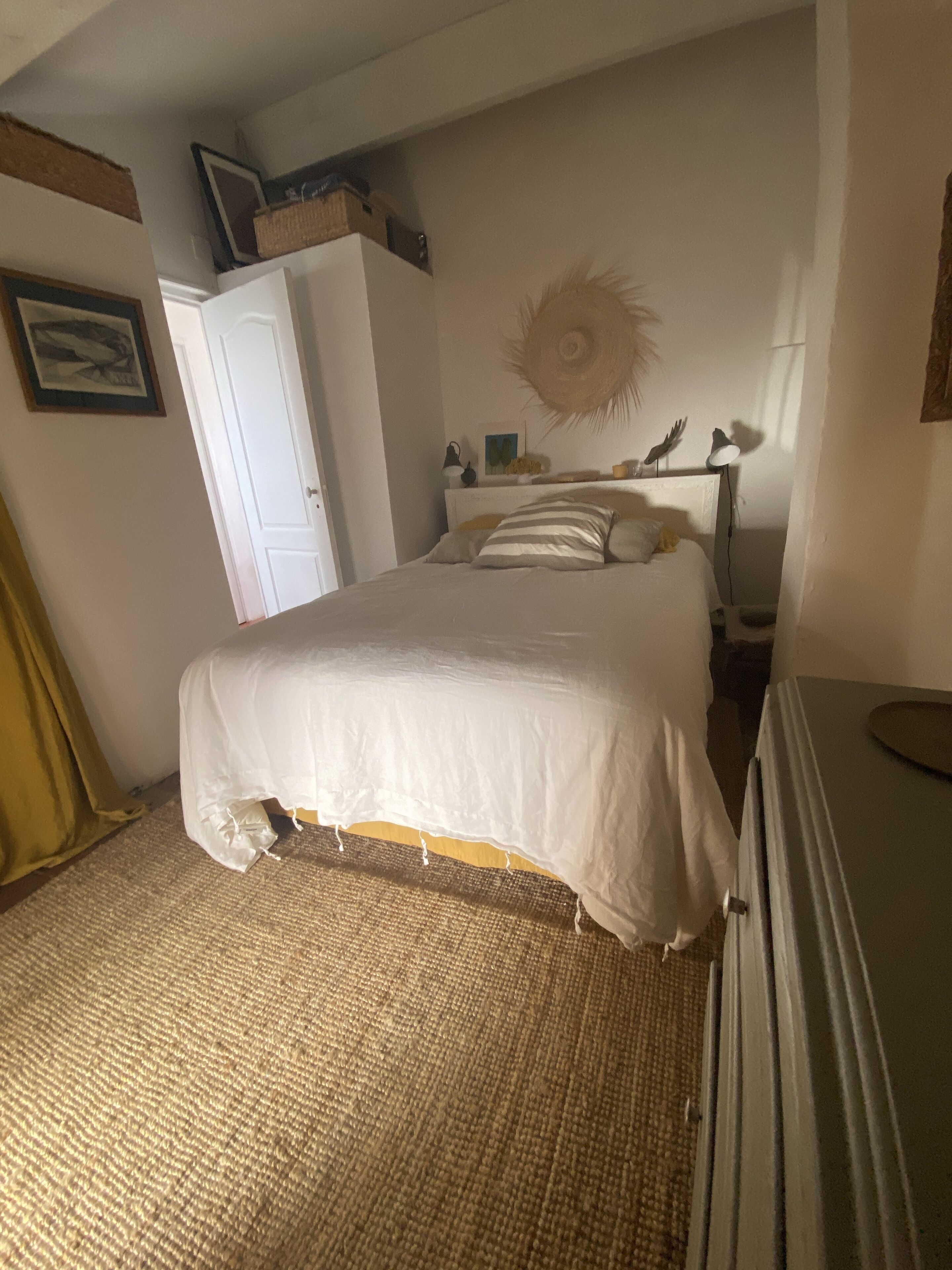 A bedroom with a bed, a wardrobe, a lamp, and a wall decoration.